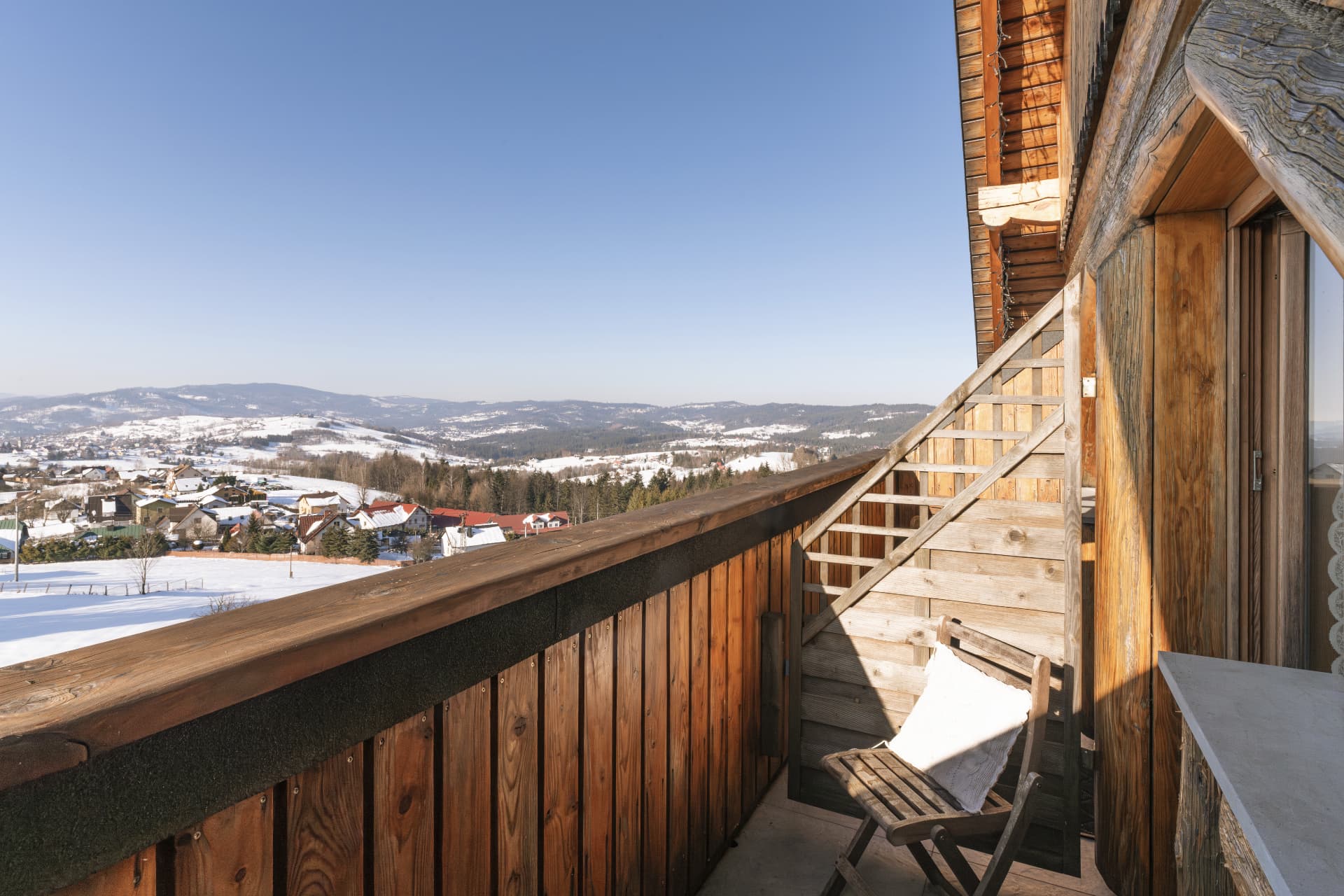 Balcony of room 8 with a chair overlooking the snowy village and hills