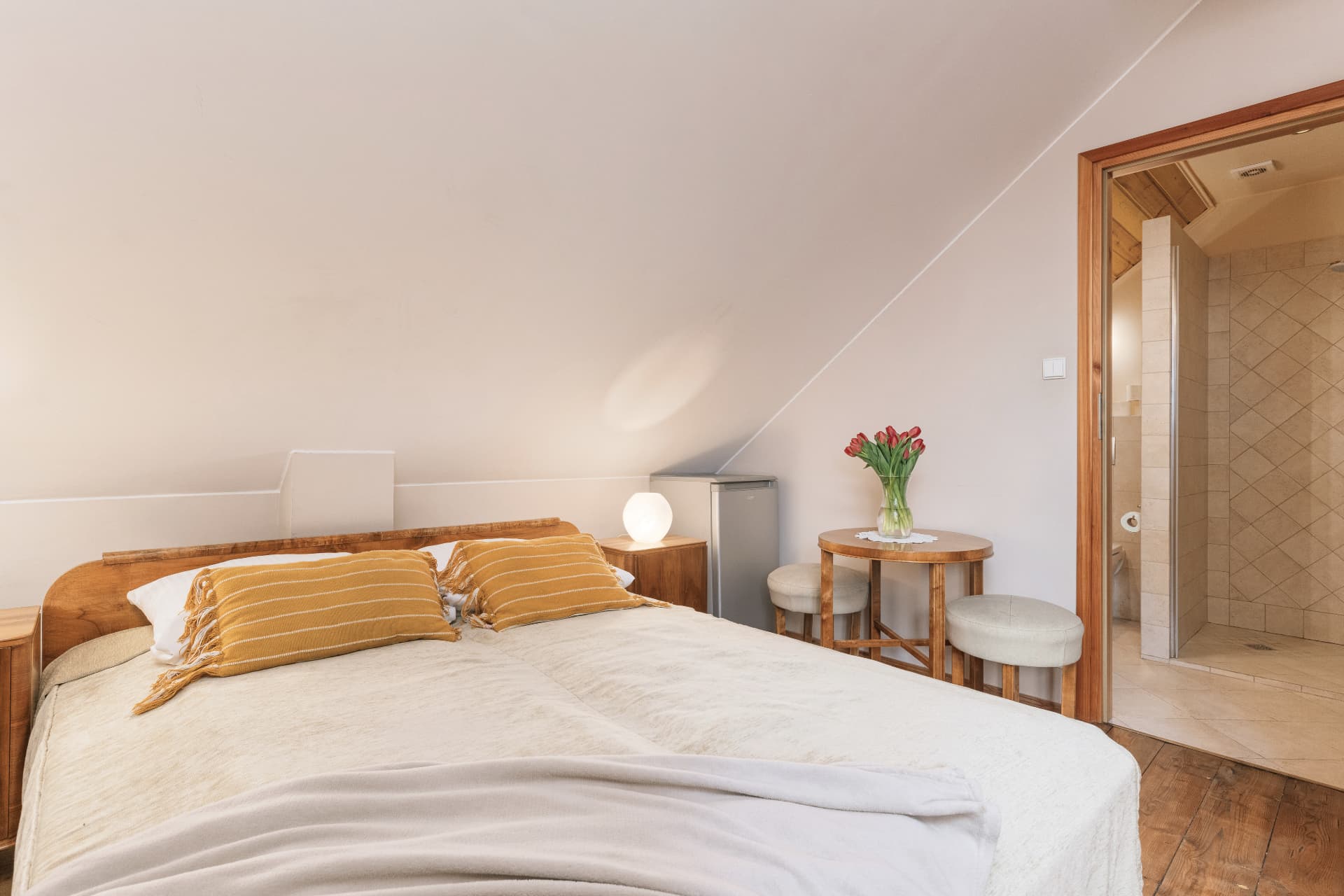 Sleeping area of room 9 with a double bed, seating table and door to the bathroom