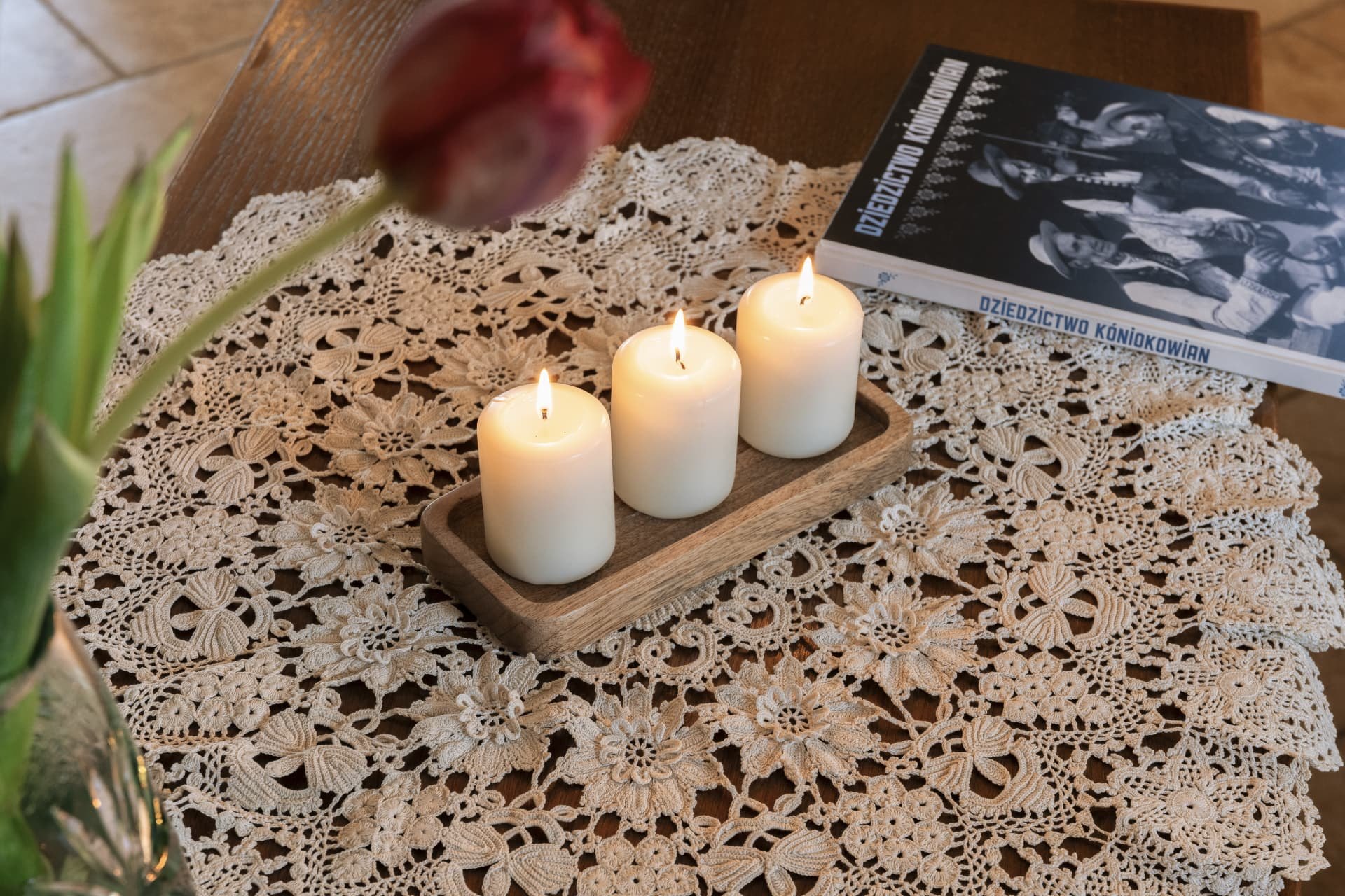Lit candles and a book on Koniaków heritage resting on a lace doily