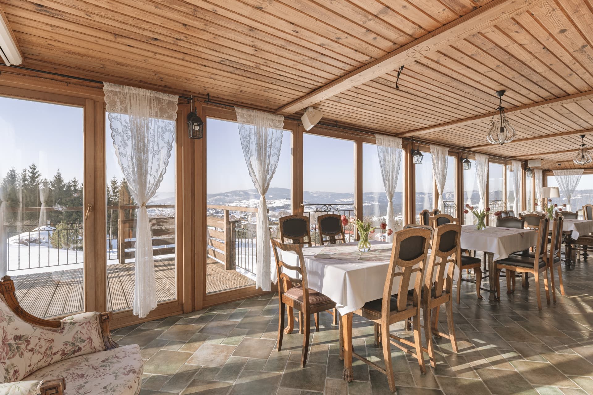 Panoramic dining veranda with lace curtains and views of the snowy valley