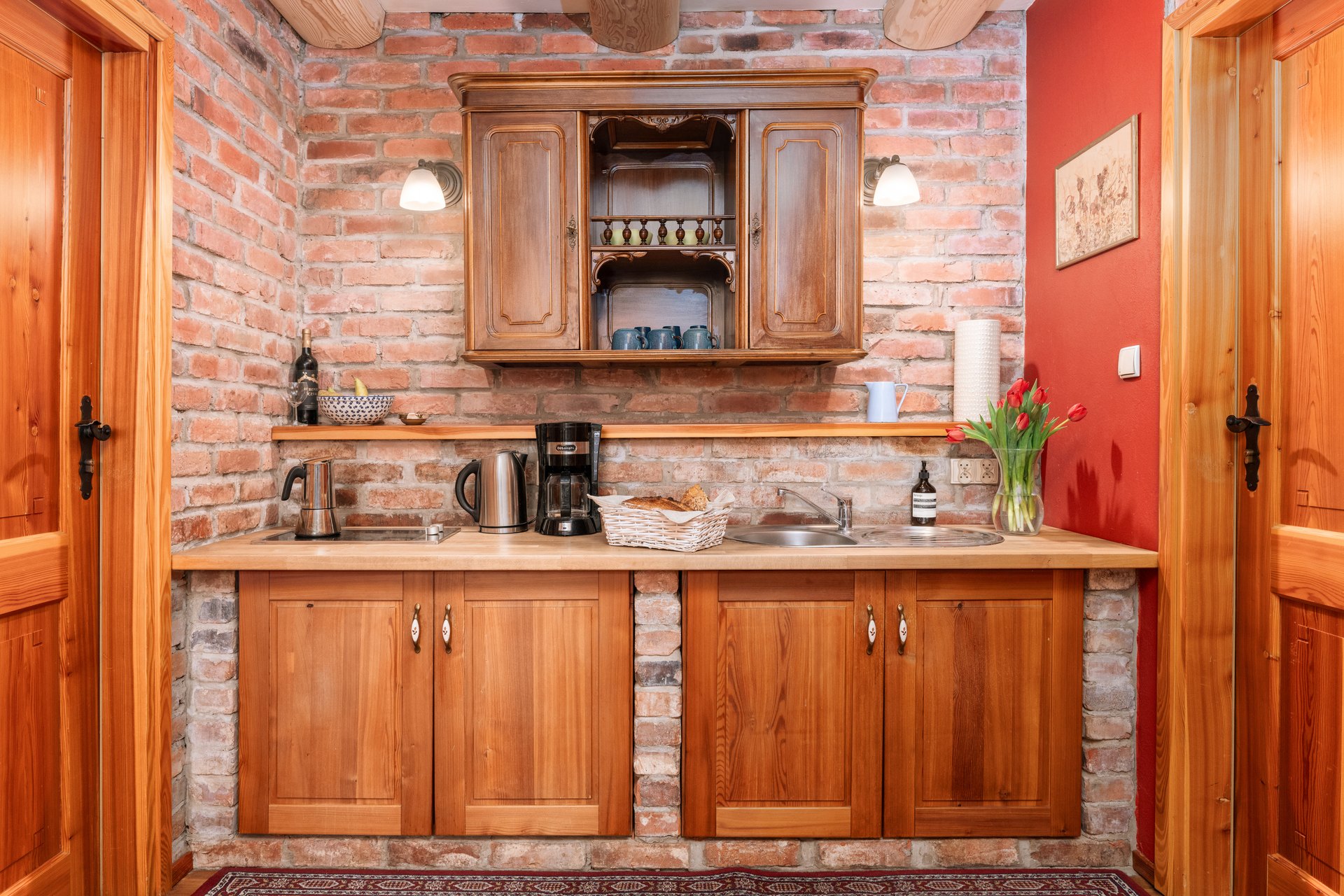 Kitchenette alcove with brick piers, a carved wooden wall cabinet and a two-burner hob
