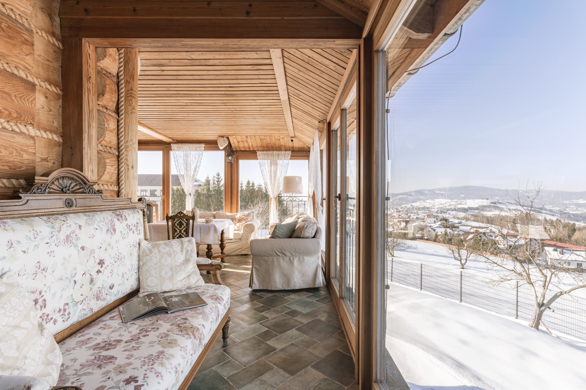 Sunroom seating beside panoramic windows overlooking the snowy mountains