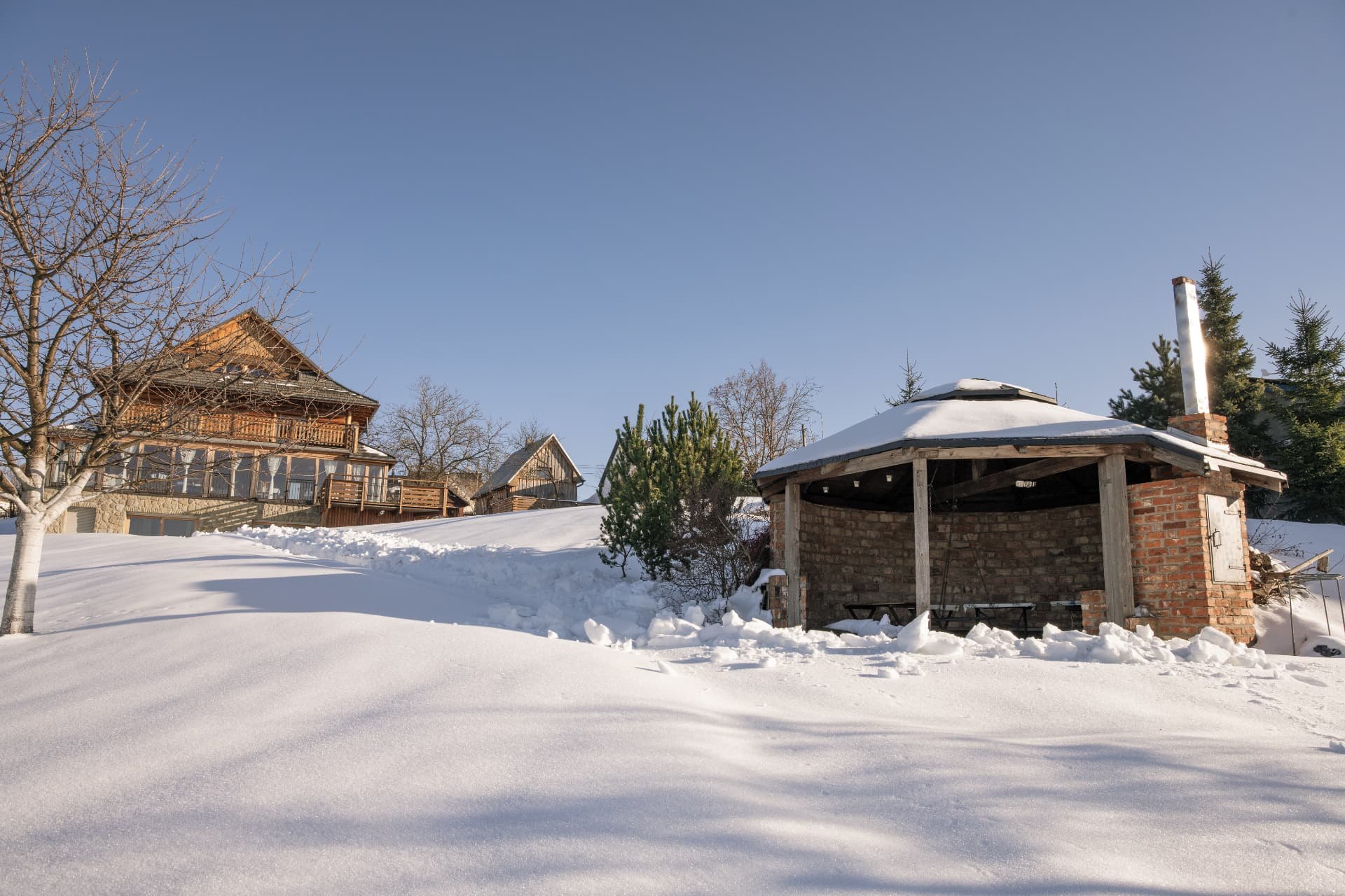 The lodge and the barbecue gazebo under deep snow on a sunny winter day