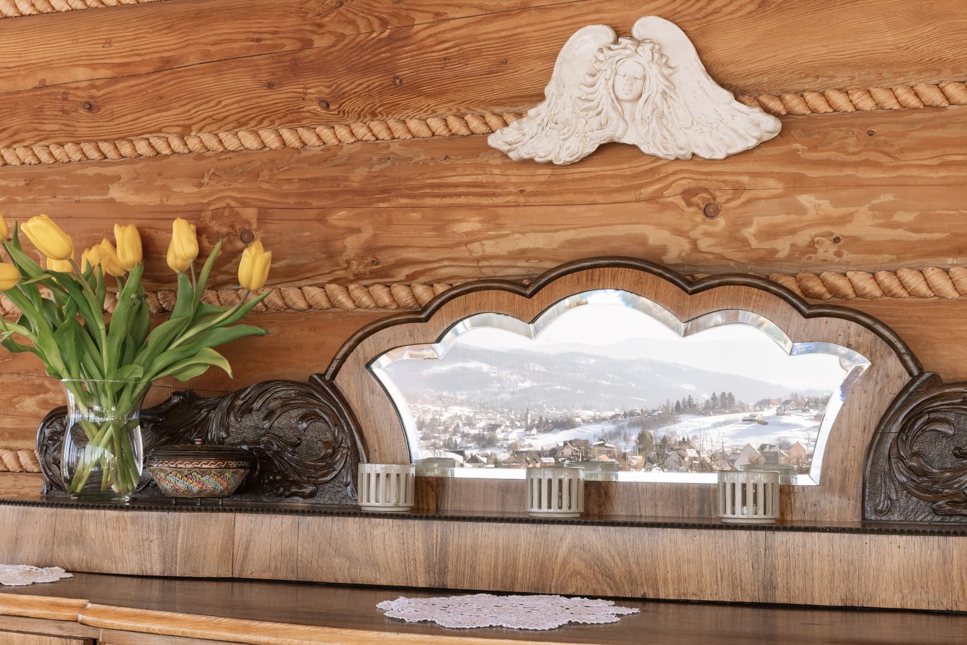 Carved wooden sideboard with a mirror reflecting the snowy village outside