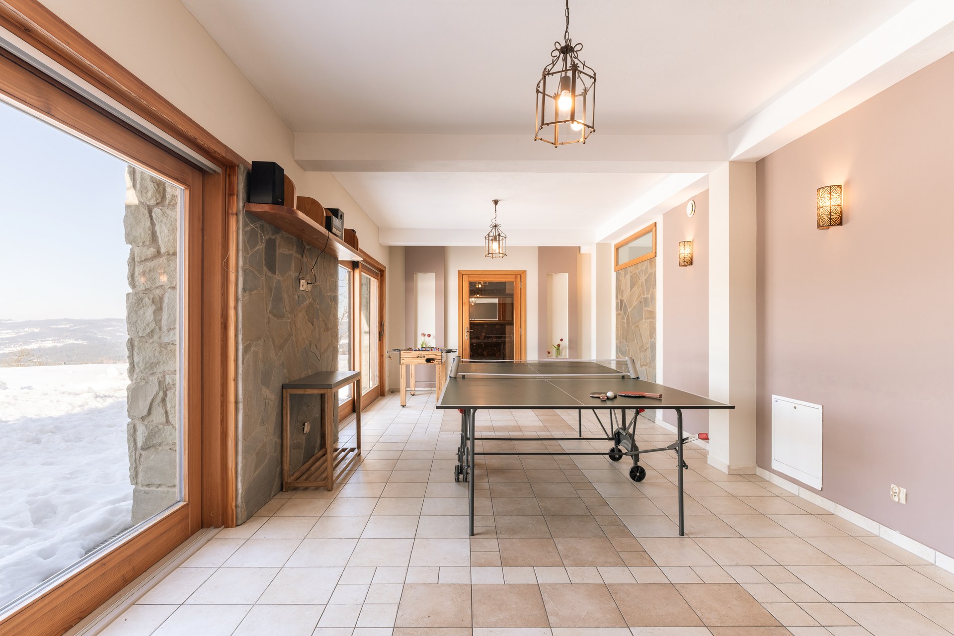 Games room with a ping-pong table, glass doors onto the snow and a foosball table