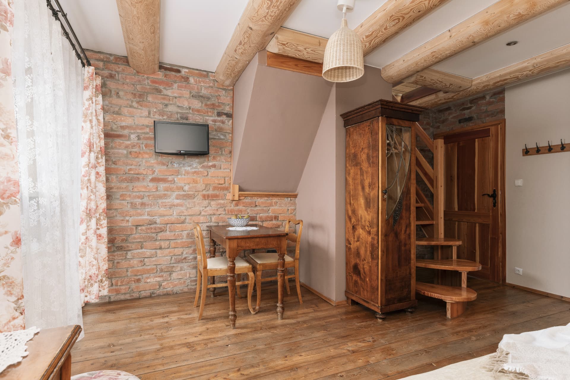 Living area of room 8 with a dining table, brick wall, TV and stairs