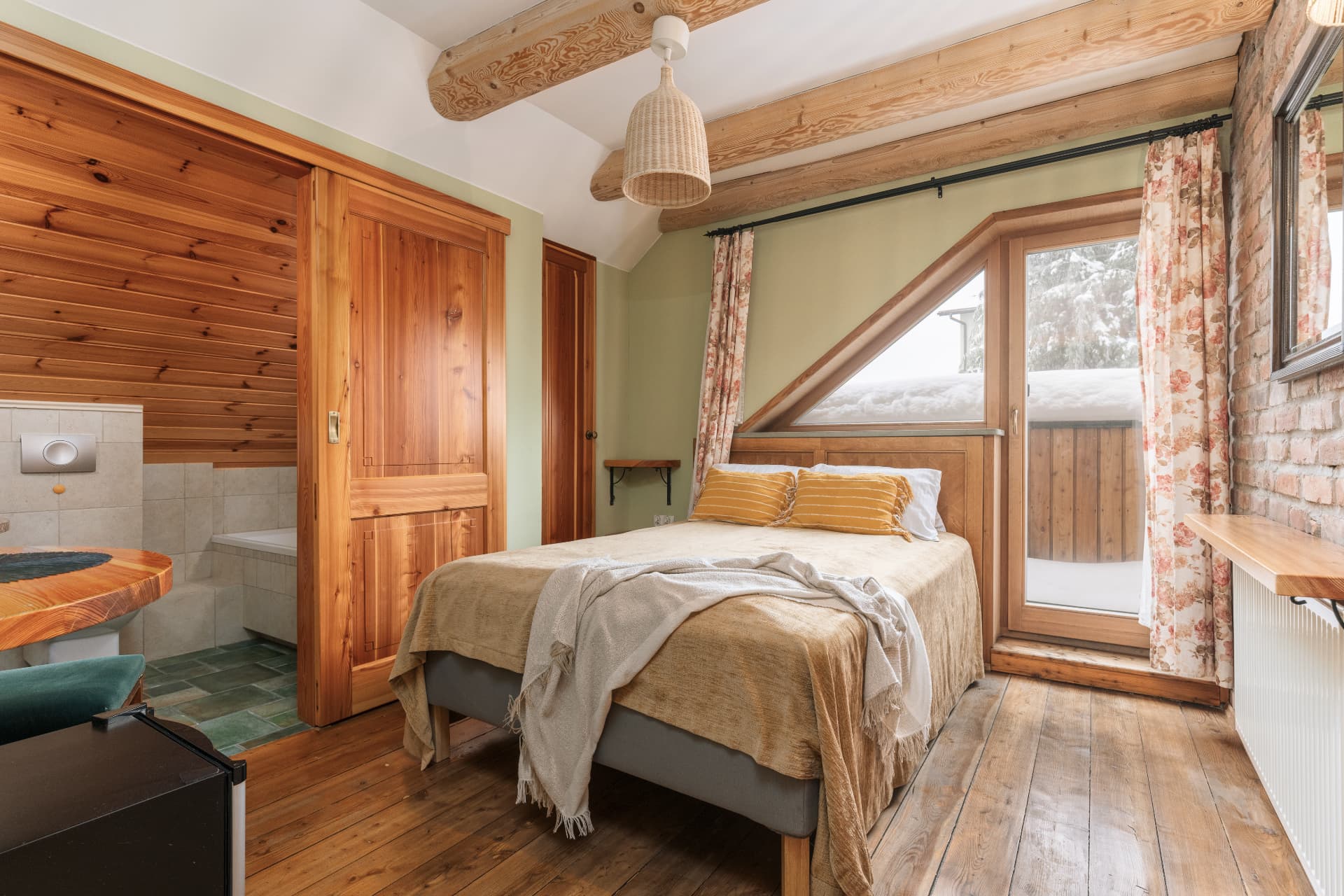 Sleeping area of room 10 with a double bed, sliding door to the bathroom and a balcony door