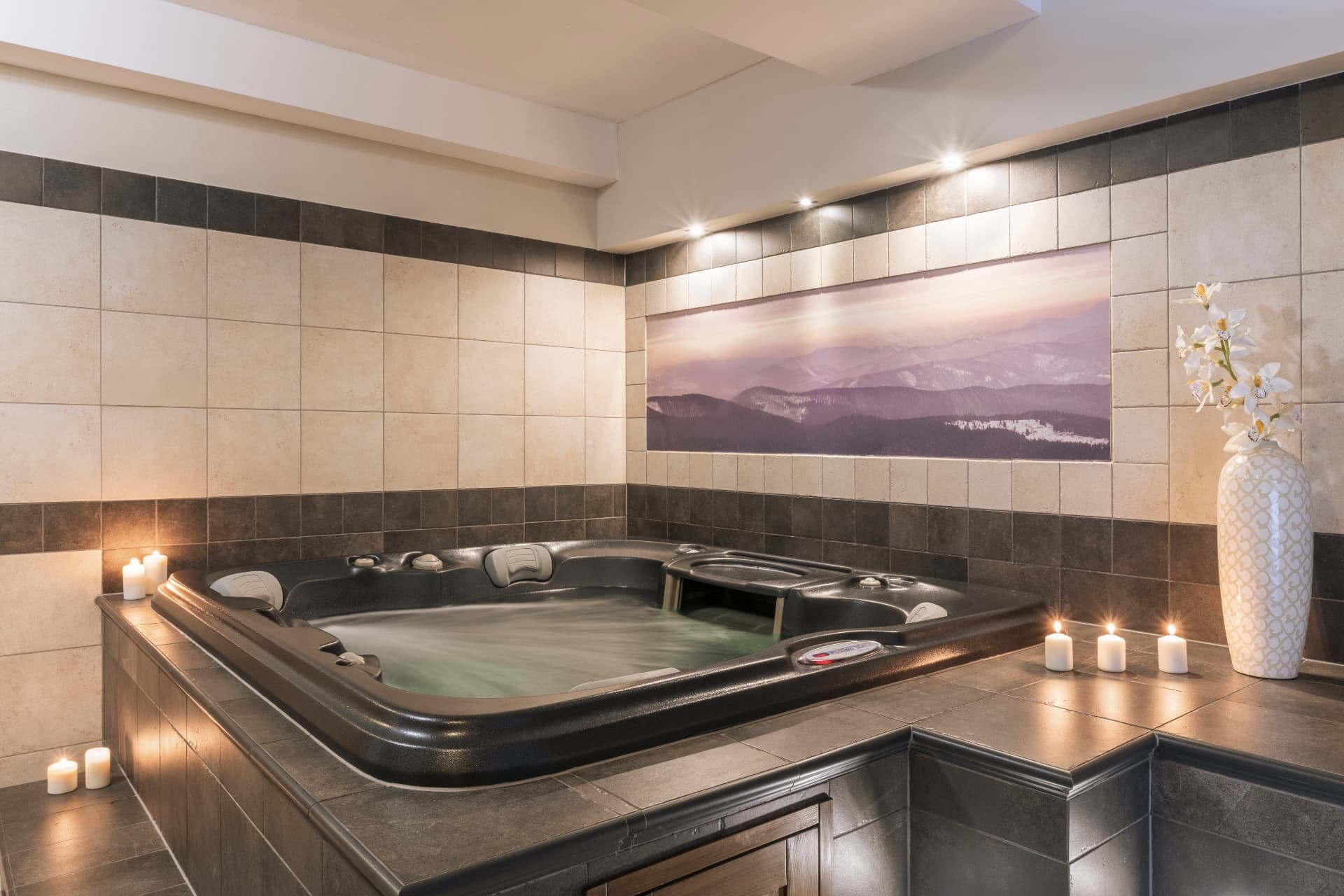 Indoor jacuzzi with candles and a mountain photo mural on the wall