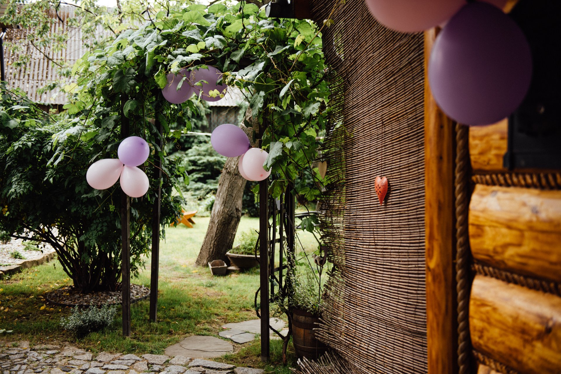 Garden trellis and log cabin exterior decorated with pastel balloons and a heart ornament