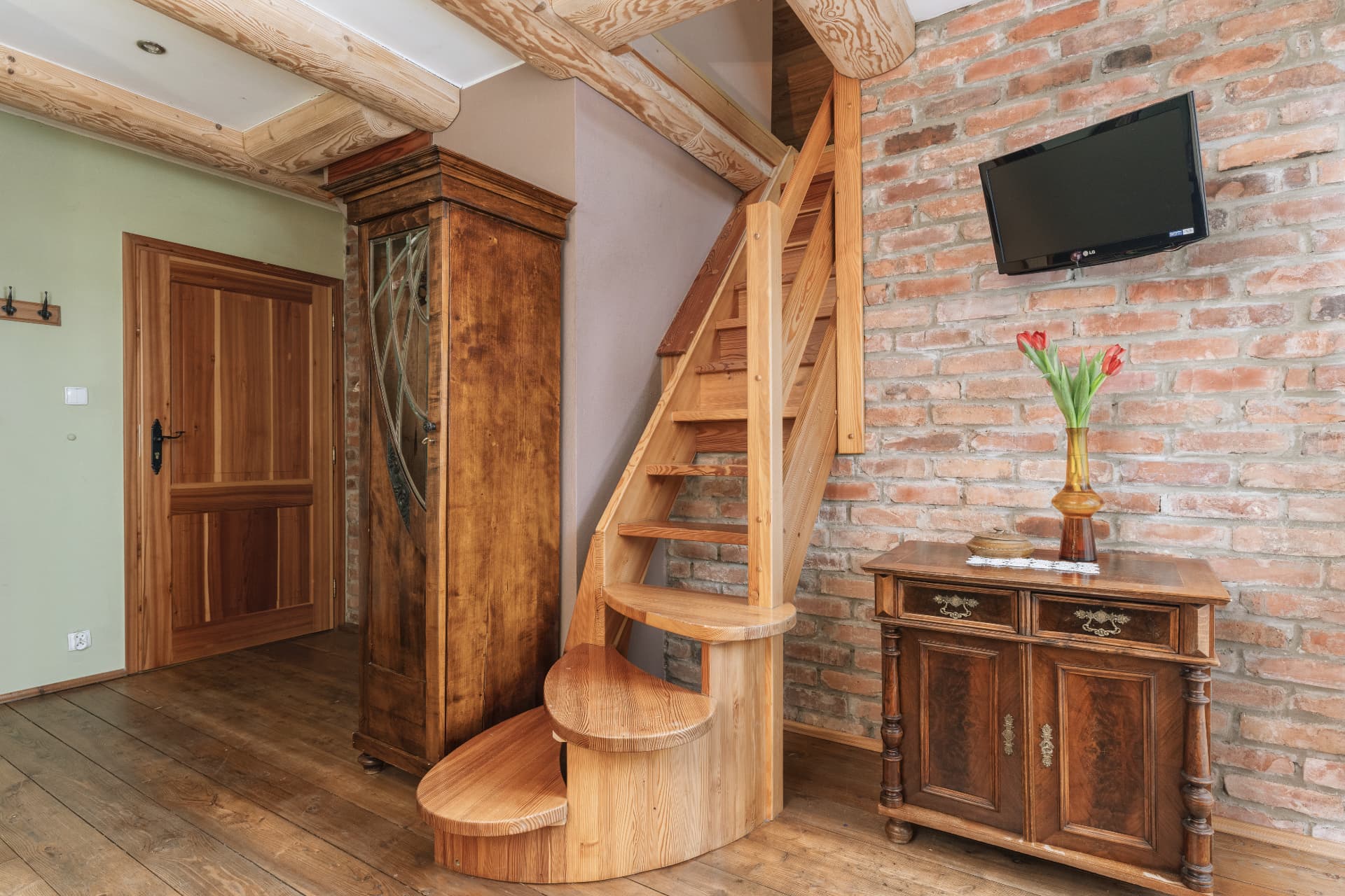 Hallway of room 7 with wooden stairs to the upper level and a wall-mounted TV