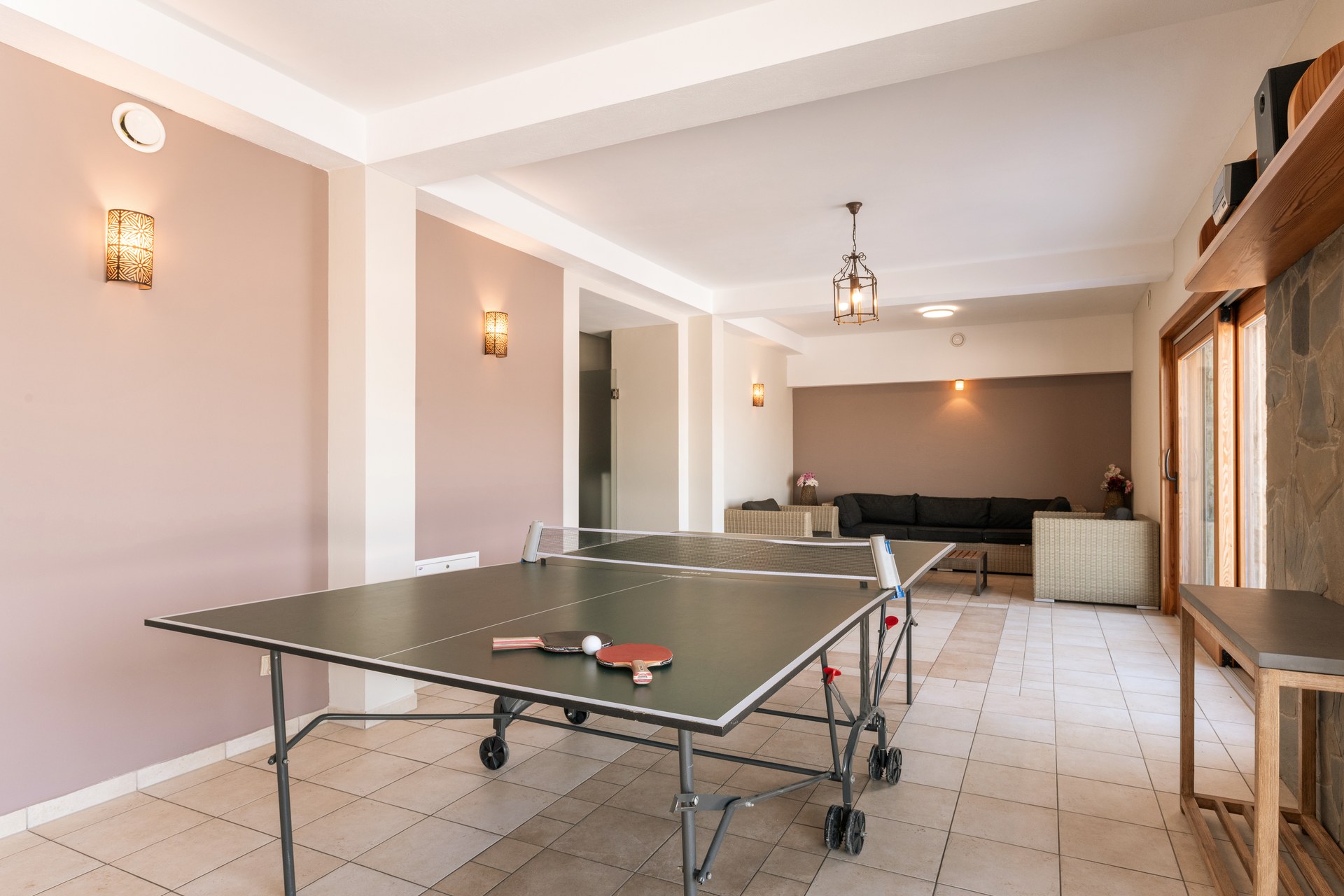 Games room with a ping-pong table and a lounge area with sofas and armchairs