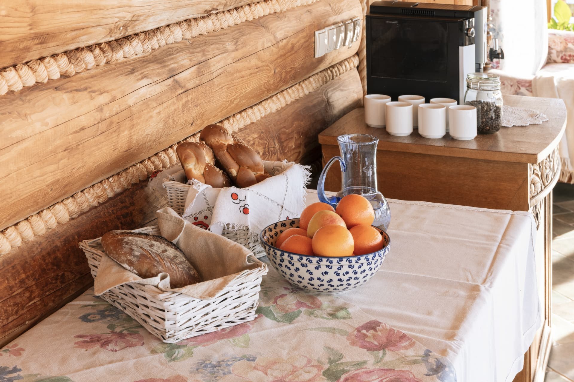 Bread baskets, oranges and coffee cups on a table beside the timber wall