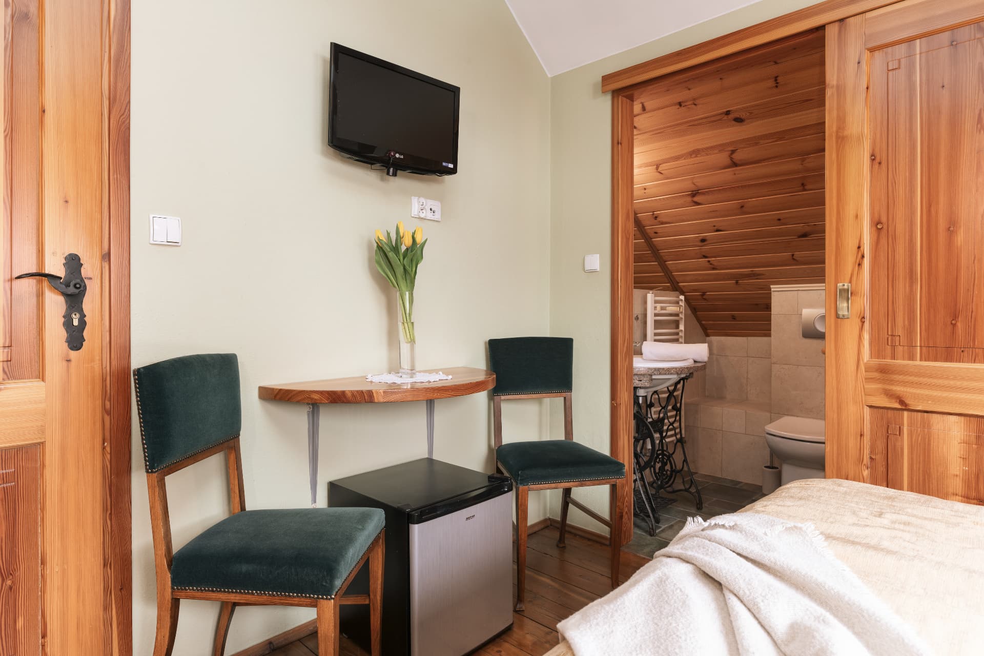 Seating corner of room 10 with two green chairs and a wall-mounted TV