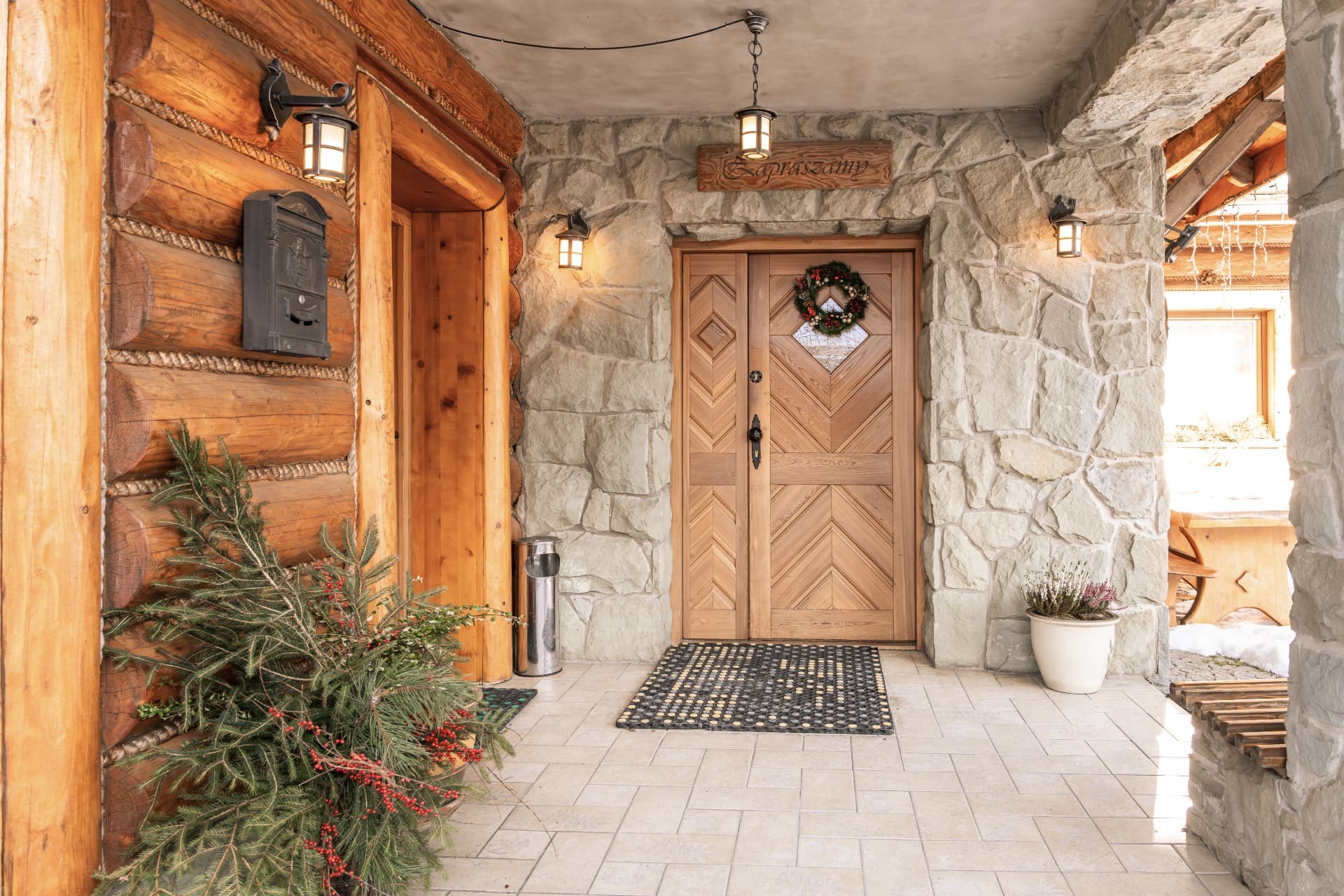 Stone and timber entrance with lanterns and a wreath on the wooden door
